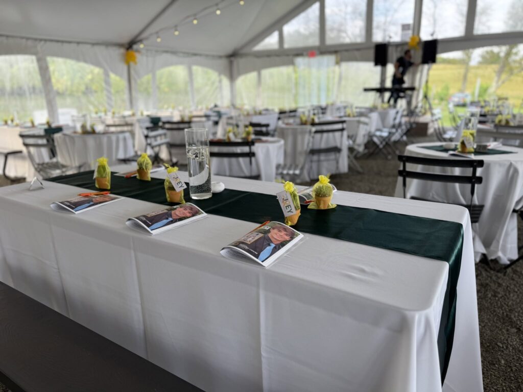 Elegant event setup under a white tent with tables dressed in white linens and green runners at Old York Cellars.