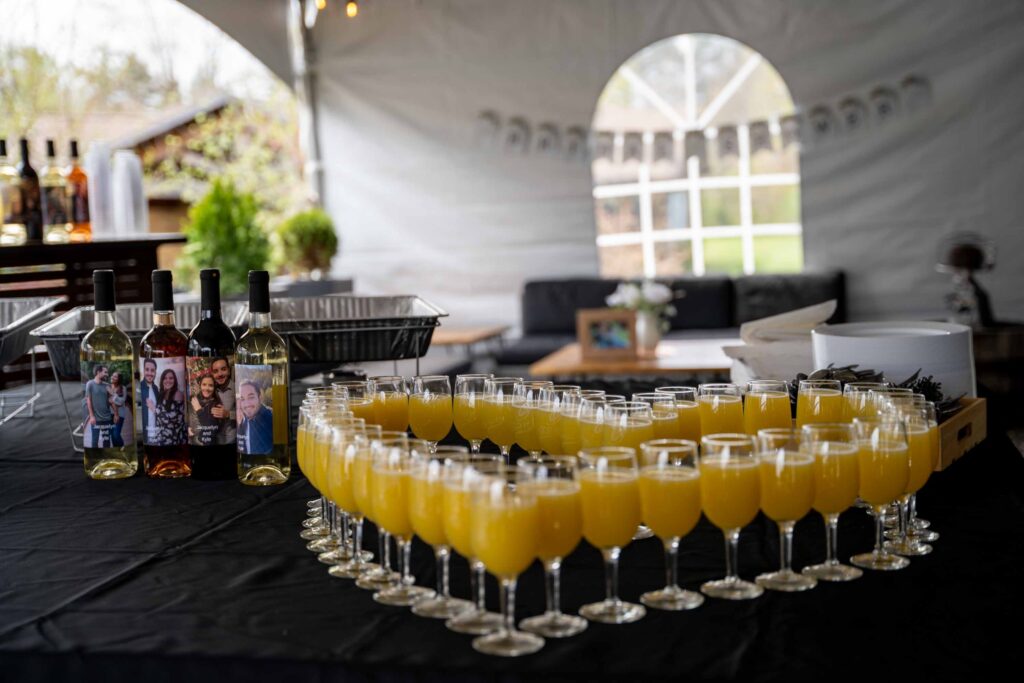 Heart‑shaped arrangement of orange drinks on a table with personalized wine bottles at Old York Cellars.