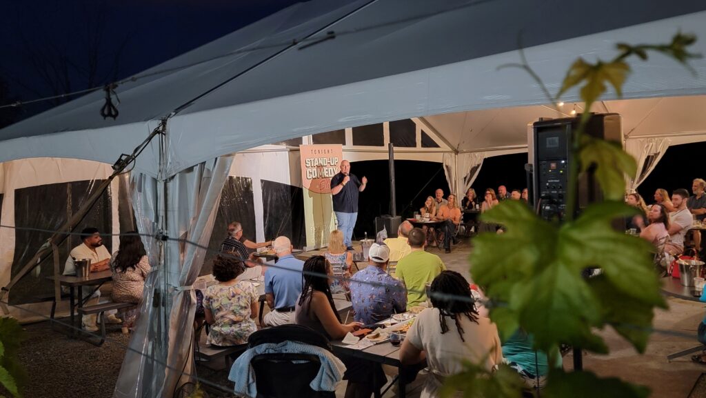 Guests seated under the Vineyard Tent at Old York Cellars enjoying Wine & Comedy Night.