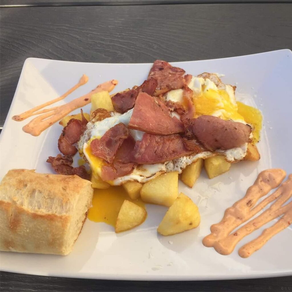 Steak and potato entrée by Chef José Diaz at Old York Cellars Winery in Ringoes, Hunterdon County, NJ, topped with sliced beef and a fried egg, served with bread and crisp breadsticks.