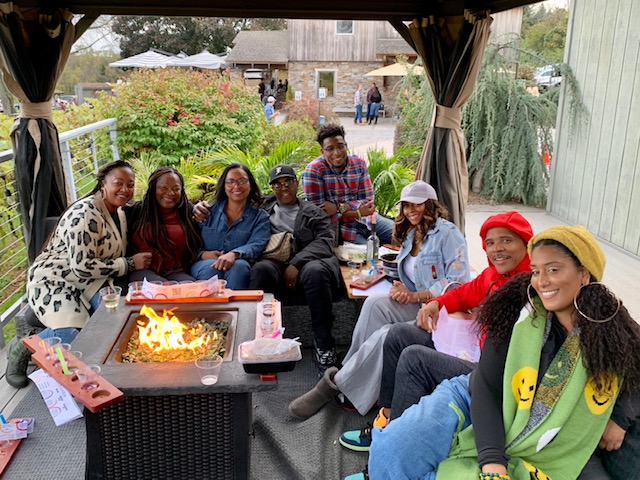 Guests relaxing around a fire‑pit table in a private wine cabana at Old York Cellars and enjoying wine, food and conversation.