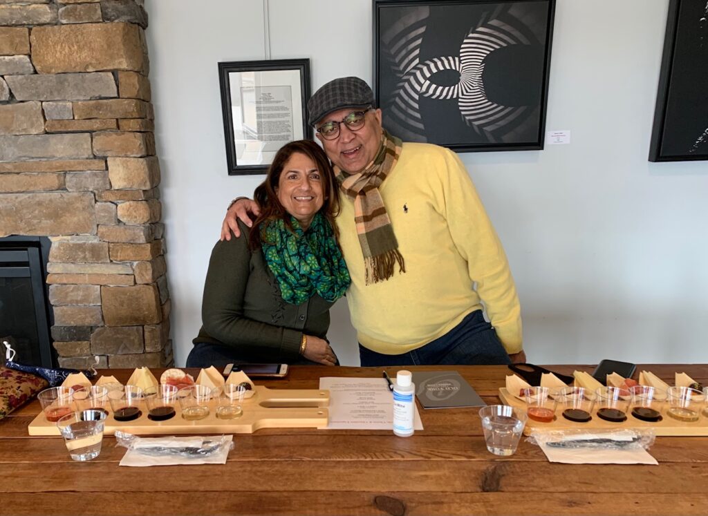Couple seated at a wooden table with wine and food tasting trays at Old York Cellars.
