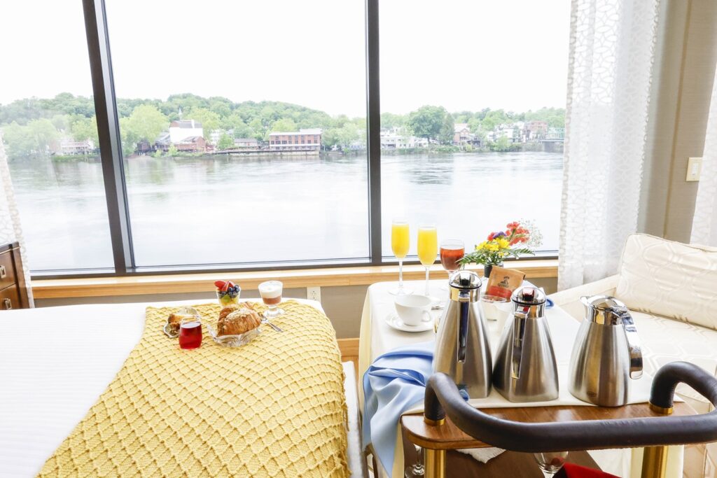 Dining table set beside large windows overlooking the Delaware River at Lambertville Station Restaurant and Inn, with teapots and breakfast settings ready for guests.