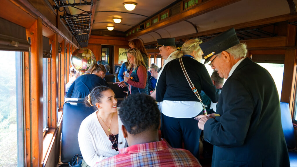 Passengers inside a vintage train car chatting with a conductor during the Hunterdon Wine Express excursion.