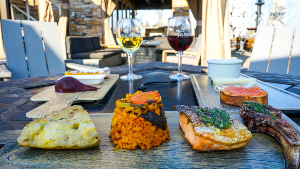 Outdoor dining table at Old York Cellars with assorted dishes and glasses of red and white wine under natural sunlight.