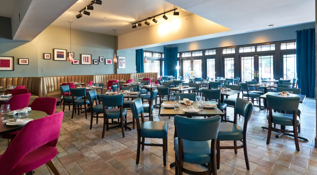 AARZU Modern Bistro restaurant dining room with blue chairs, set tables, and large windows letting in natural light.