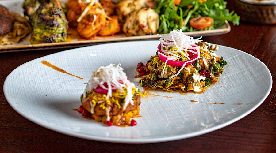 wo beautifully plated servings of a layered savory dish topped with shredded garnish and red onions, surrounded by fresh greens — a vibrant entrée at Aarzu Modern Indian Bistro in Freehold, NJ paired perfectly with Old York Cellars wines.