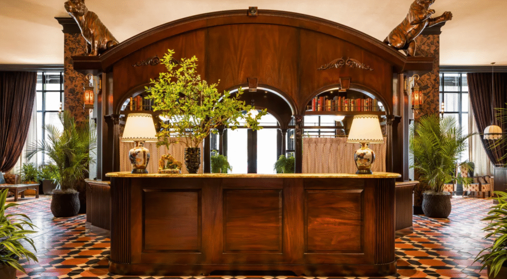Lobby of Graduate by Hilton Princeton featuring a large wooden reception desk with decorative plants and arched architectural details.