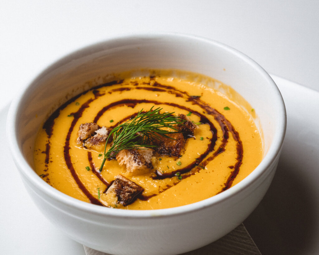 Homemade soup at Jessica's in Fanwood, NJ. A bowl of creamy orange soup drizzled with balsamic glaze and garnished with croutons and fresh herbs, ideal for enjoying with a glass of Old York Cellars Chardonnay.