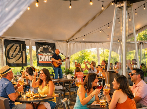 Guests dining under the Vineyard Tent at Old York Cellars during a live music performance.