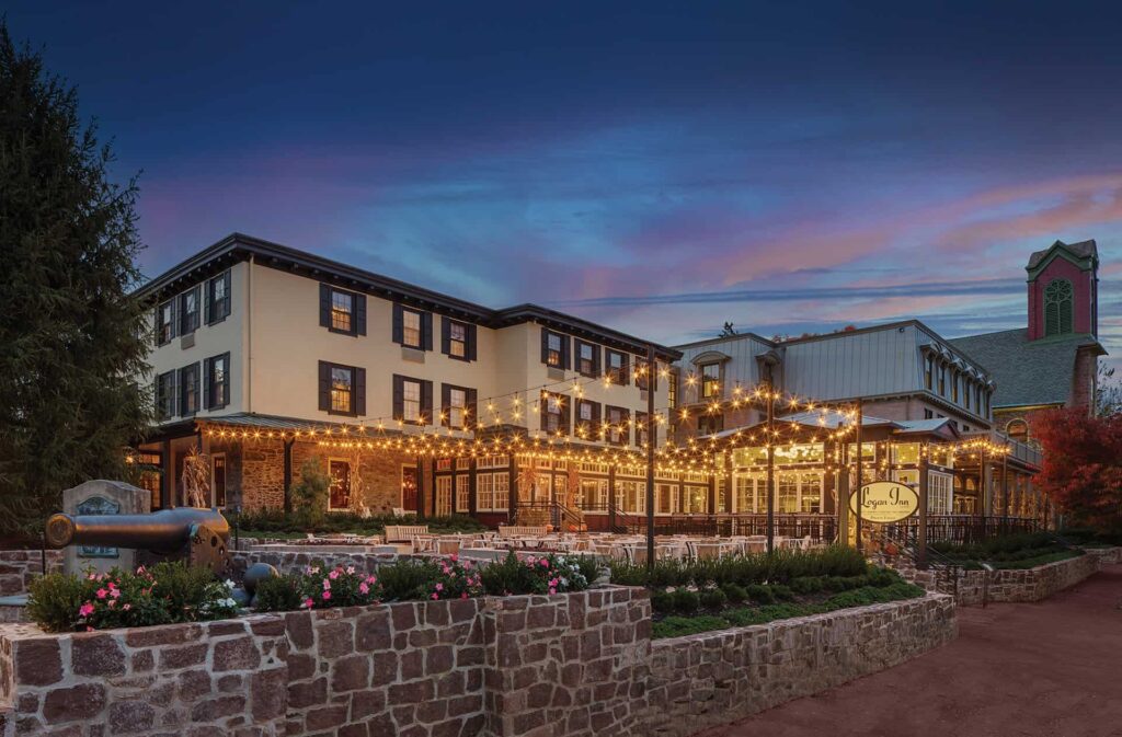 Exterior of Logan Inn in New Hope, Pennsylvania, illuminated at dusk with warm lighting and stone architecture surrounded by landscaped grounds.