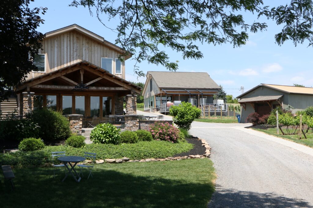 Old York Cellars winery Tasting Room building and the winemaker's building surrounded by landscaped greenery under a clear blue sky.