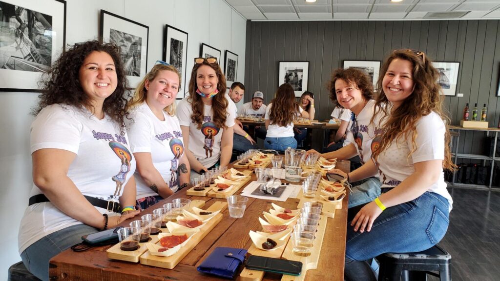 Group of friends enjoying a wine and chocolate tasting indoors at Old York Cellars, smiling around a long wooden table.