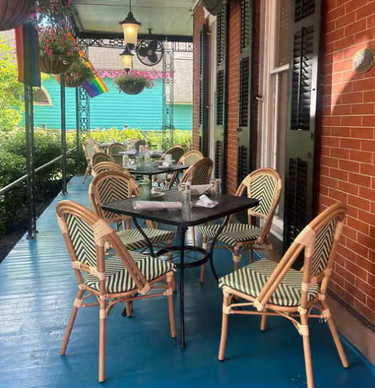 Colorful outdoor patio with wicker chairs, tables, and hanging flower baskets at Under the Moon Café.