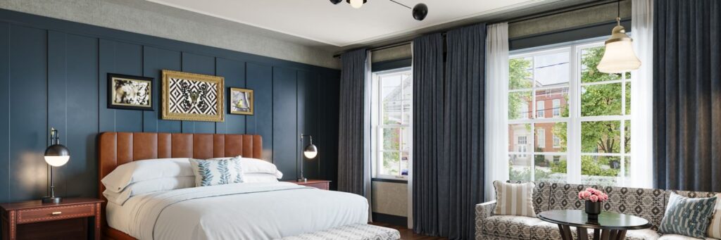 Elegant guest room at The Union Hotel with a king bed, soft lighting, and large windows draped in navy curtains, showcasing Marriott’s Tribute Portfolio design aesthetic.