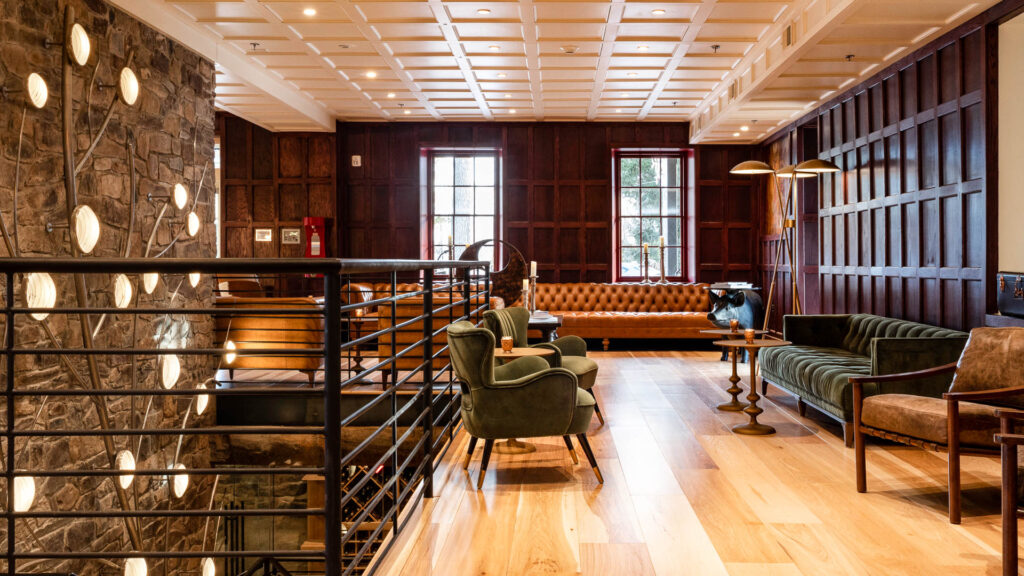 Interior lounge at Logan Inn featuring stone walls, wood floors, and modern seating areas with large windows and natural light.