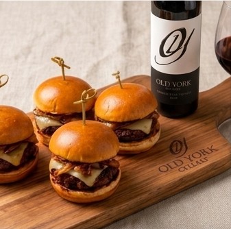 Philadelphia cheesesteak with shaved beef and melted cheese served on a metal tray next to a bottle and glass of Old York Cellars Cabernet Sauvignon red wine for Eagles game day tailgating.