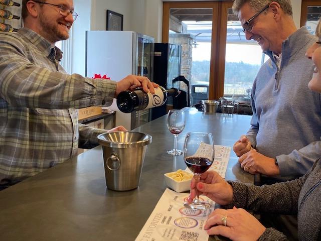 Guests enjoy a red‑wine tasting at Old York Cellars in Ringoes, NJ. A winery host pours wine at a modern counter with tasting mats and cheese samples, highlighting Central NJ wine and food pairings.
