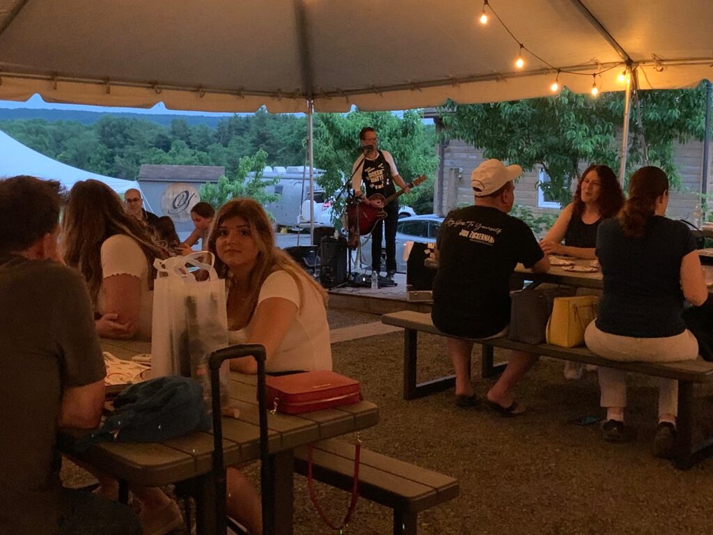 Guests enjoying brunch under the Vineyard Tent at Old York Cellars Winery in Ringoes, NJ, listening to live music with wine and food on the tables.