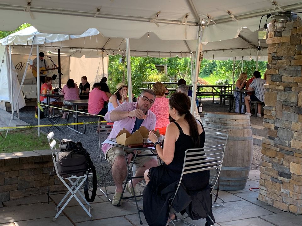 Outdoor brunch crowd seated under a white tent at Old York Cellars Winery in Hunterdon County, NJ, surrounded by vineyard views and rustic stone accents.