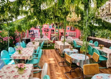 Colorful interior of Uncle Rocco in Hoboken, NJ, with floral tablecloths, chandeliers, and greenery hanging from the ceiling.