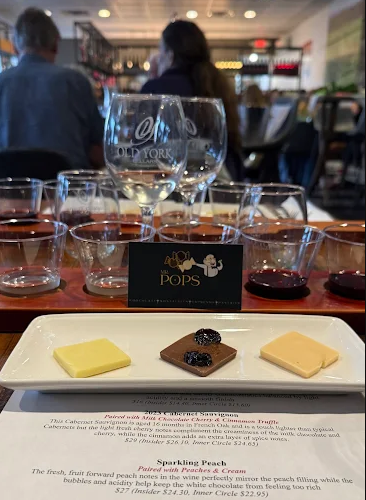 Wine and cheese tasting at Old York Cellars in Ringoes, NJ. A wooden tray holds glasses of wine with a plate of chocolate truffle samples, showcasing Central NJ wine and food pairings at the winery’s tasting room.
