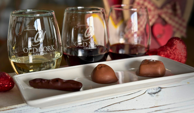 Close‑up of Old York Cellars wine glasses filled with red wine beside a tray of artisan chocolates in Ringoes, NJ. The pairing highlights the winery’s signature wine and chocolate tasting experience in Central NJ.