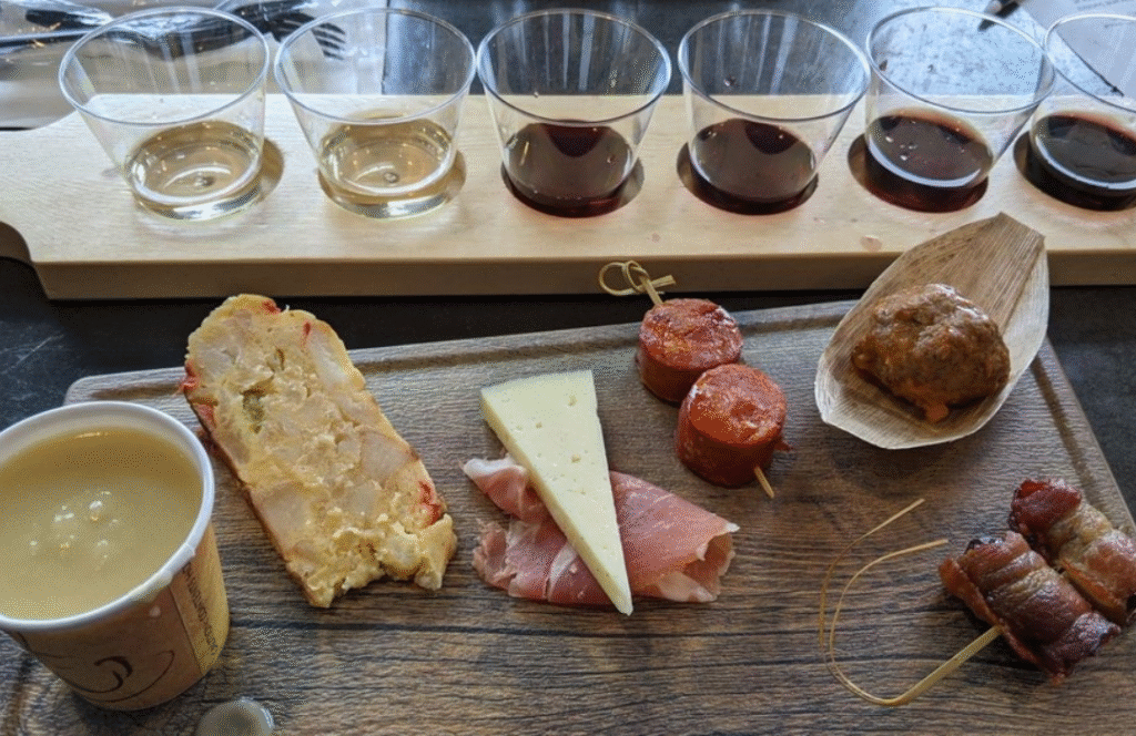 Wine and tapas pairing board at Old York Cellars in Ringoes, NJ featuring tasting glasses of wine with assorted bites including cheese, cured meats, sausage, bread, and soup. A rustic presentation highlighting Central NJ wine and food pairing experiences.